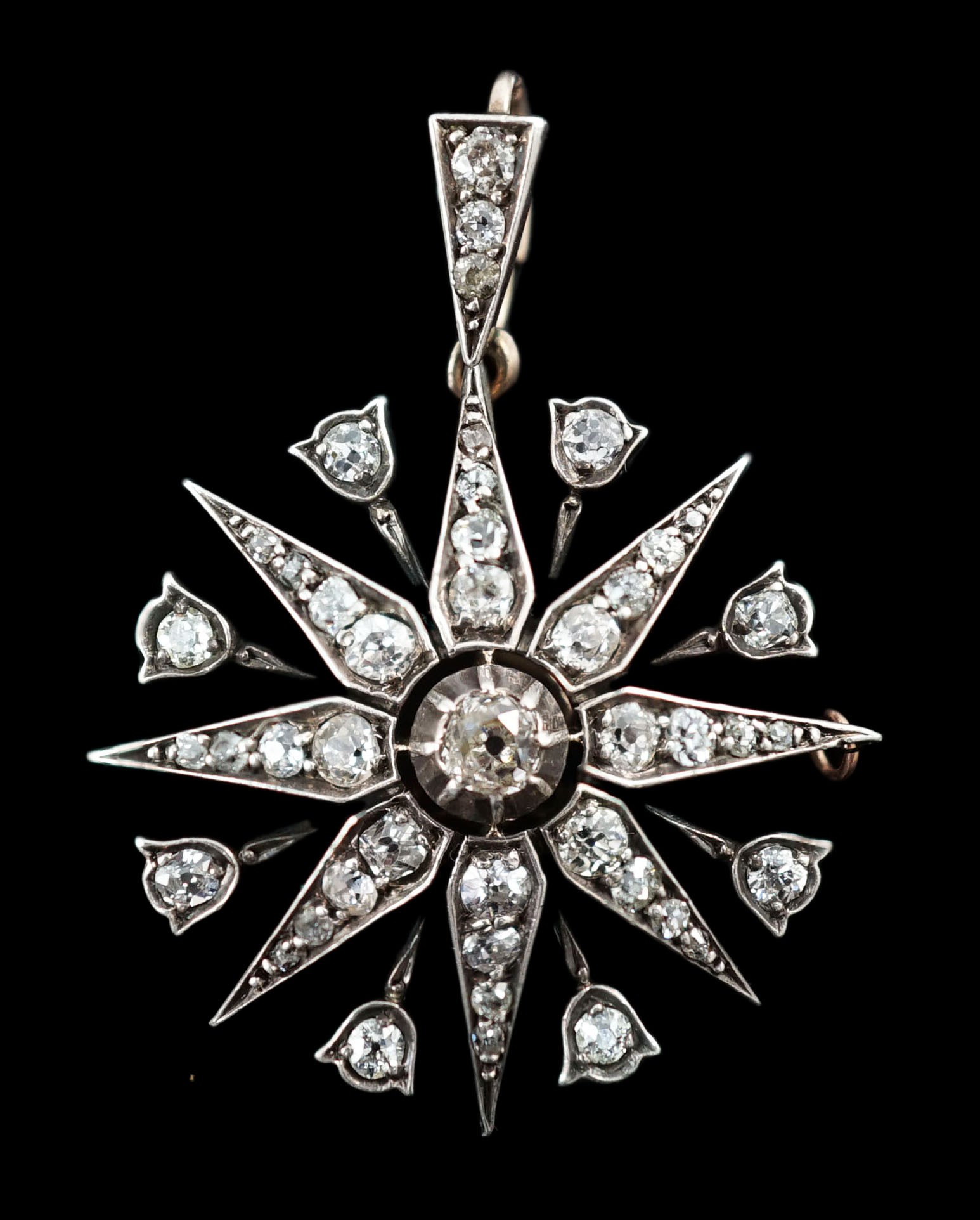 A late Victorian gold, silver and diamond cluster set starburst pendant